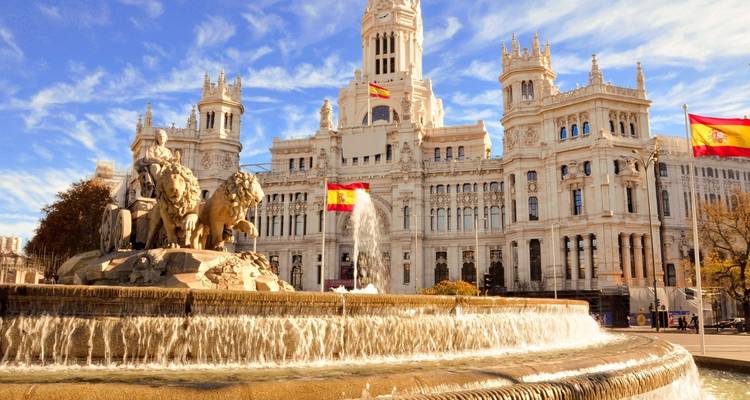 Palais de Cibeles avec une fontaine et des drapeaux espagnols.