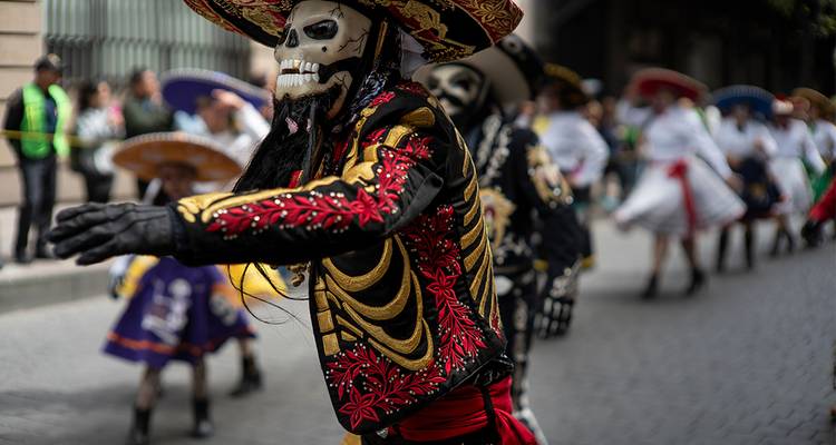 Person in einem Skelett-Kostüm, die in einer Parade tanzt.