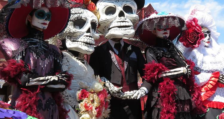 Gruppe von Menschen in großen Skelett-Kostümen während eines Festivals.