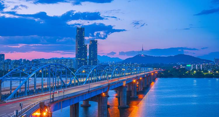 Avondlandschap van Seouls skyline met verlichte brug over de Han-rivier en N Seoul Tower daarachter.