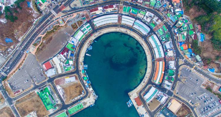 Kleurig luchtfoto van een perfect rond haventje omgeven door dicht opeengepakte Koreaanse gebouwen.
