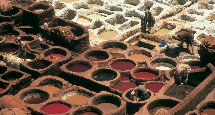 Tannerie traditionnelle marocaine avec des ouvriers teignant le cuir.
