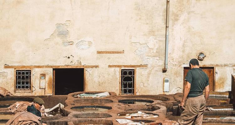 Ouvriers dans une tannerie traitant le cuir dans un environnement extérieur.