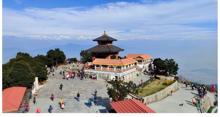 Temple on a hilltop with people exploring around and mountains in the background.
