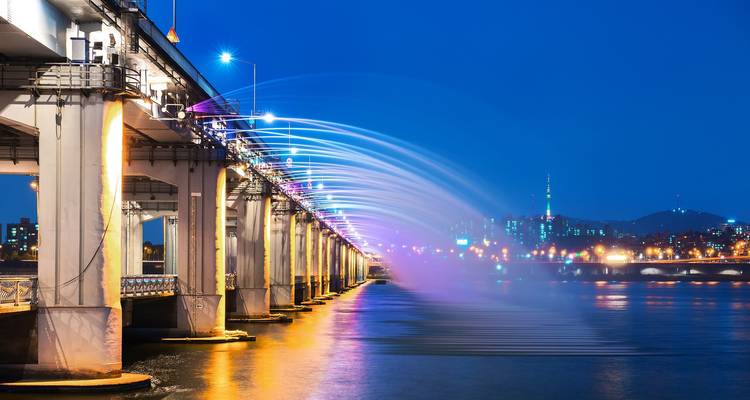 Regenboogfontein van de Banpo-brug spuit over de Han-rivier met Seouls skyline in de nacht