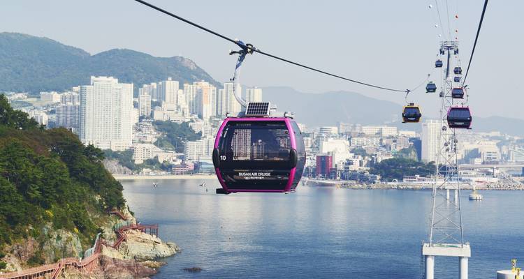 Kleurrijke kabelbanen glijden over de kust en skyline van Busan