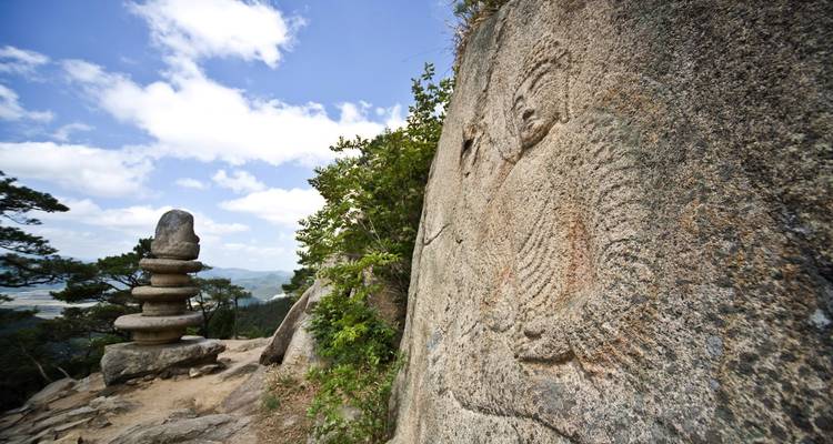Oude Boeddha-reliëf en stenen pagode staan op een rotsachtige Koreaanse berghelling