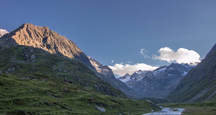 Vue de vallée avec rivière et montagnes environnantes.