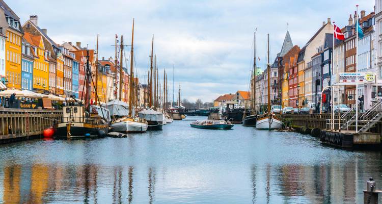 Canal view with moored boats and colorful buildings.