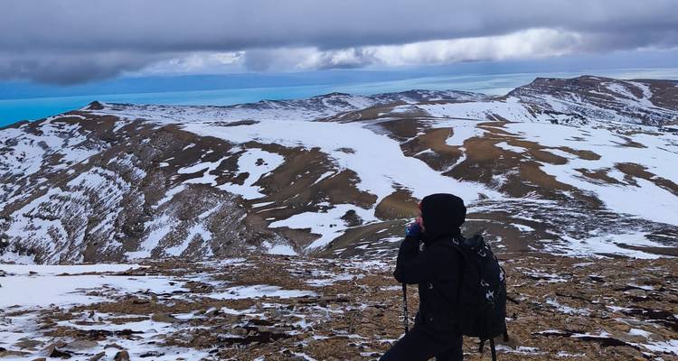 Hiker taking a photo on a snowy mountain with expansive views.