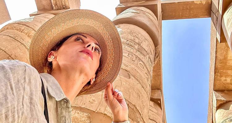 Woman posing in front of ancient Egyptian architecture wearing a sunhat.