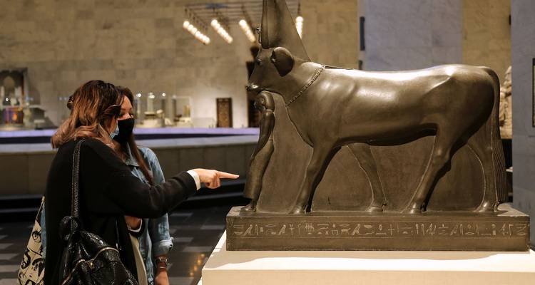 Museum visitors observing an ancient Egyptian statue.