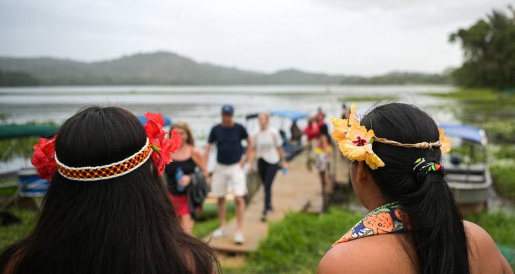Des personnes en tenue traditionnelle debout sur un quai près de l'eau.