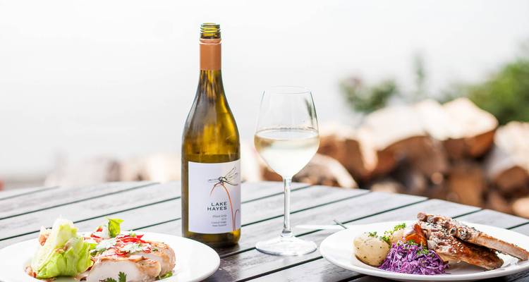 Botella de vino y platos de comida en una mesa.