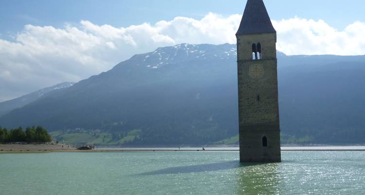 Een kerktoren die gedeeltelijk ondergedompeld is in een meer.