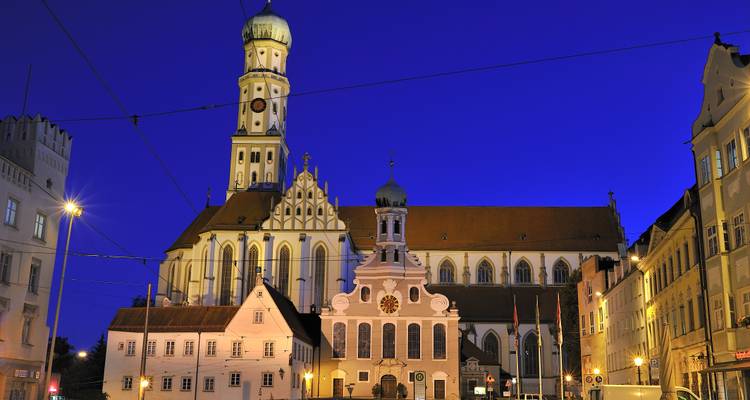 Nachtaanzicht van een historische kerk in Augsburg met avondverlichting.