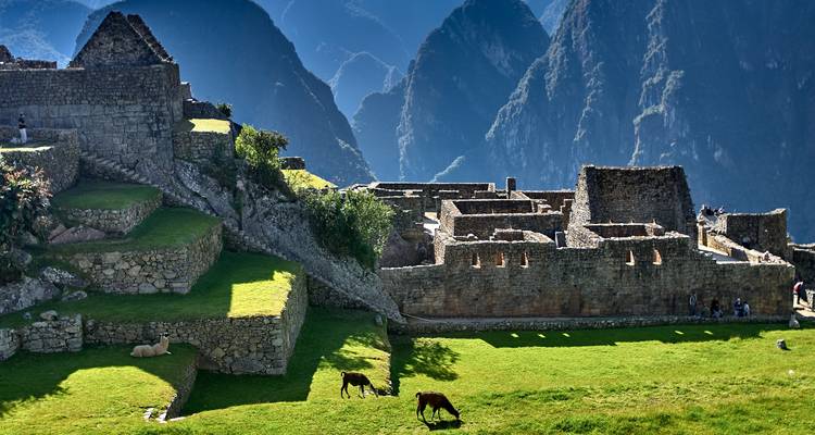 Oude stenen ruïnes met grasachtige terrassen in een bergachtig gebied.