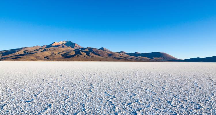 Uitgestrekte zoutvlakte met bergketen in de verte.