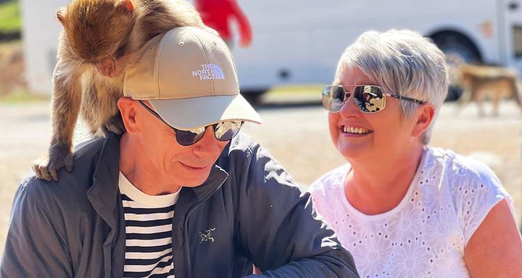 Un couple avec un singe sur l'épaule de l'homme portant des lunettes de soleil