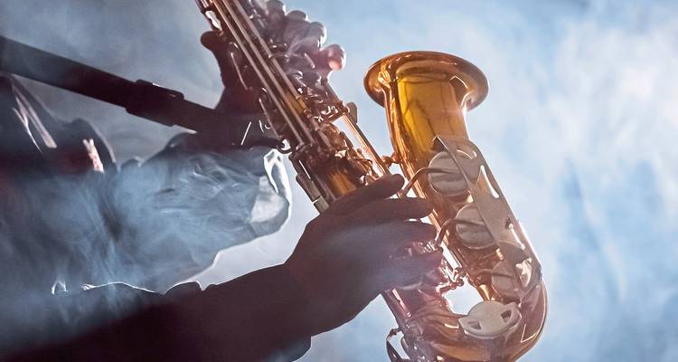 Musicien jouant du saxophone avec un éclairage dramatique.