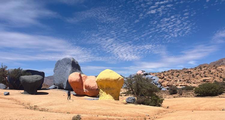Des roches peintes colorées dans un paysage désertique sous un ciel bleu.