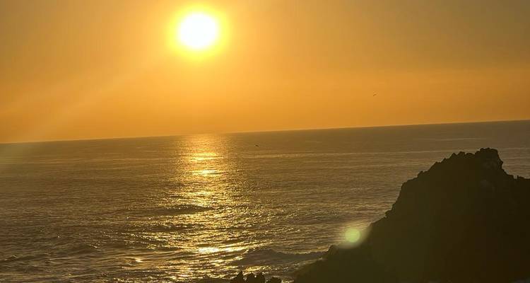 Une vue panoramique sur l'océan avec le soleil se couchant à l'horizon.