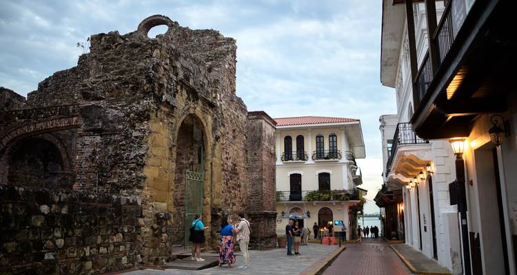 Rue pittoresque avec ruines anciennes, bâtiments et gens.