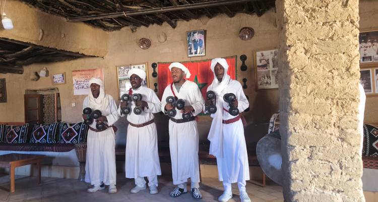 Group of men in traditional clothing with instruments.