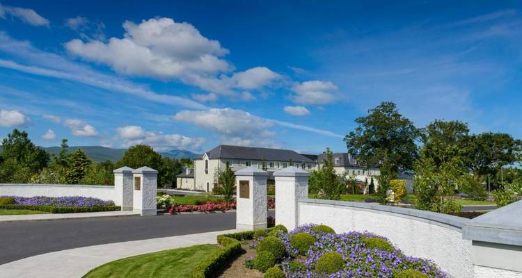 Spacious garden with decorative pillars and a building in the background under a blue sky.