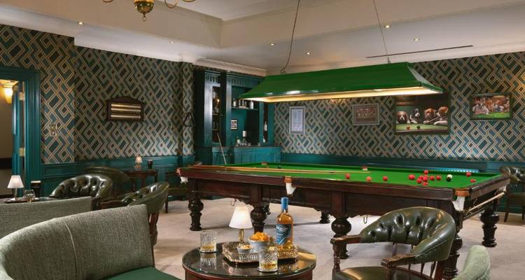 Interior of a luxurious billiard room with a green table and elegant seating.