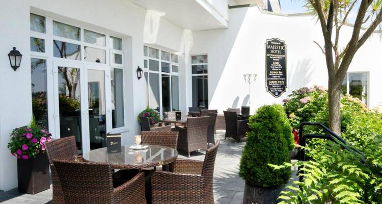 Outdoor terrace of Majestic Hotel with wicker furniture and colorful flowers.