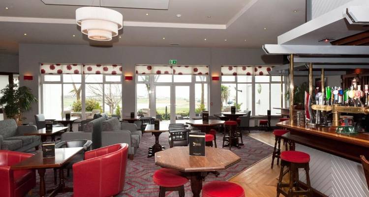 Modern pub interior with red seats and a bar counter.