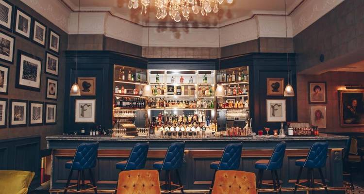 Luxurious bar with chandeliers and blue chairs.