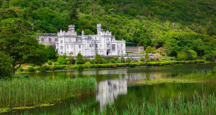 Historisches Schloss mit üppig grüner Umgebung neben einem See.