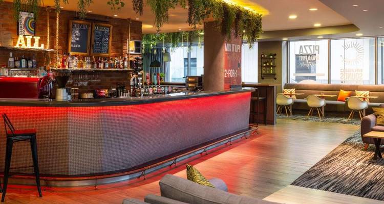 Zone bar avec comptoir éclairé et sièges.