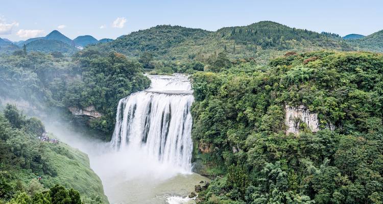Ein massiver, mehrstufiger Wasserfall, der in eine Flussschlucht inmitten eines dichten Tropenwaldes stürzt.