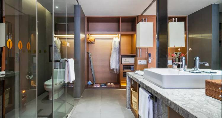 Modernes Hotelbadezimmer mit Glasdusche, großem Waschtisch, offener Garderobe und eleganten Armaturen