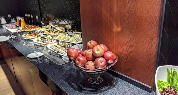Buffet with a variety of foods, including apples and sandwiches.