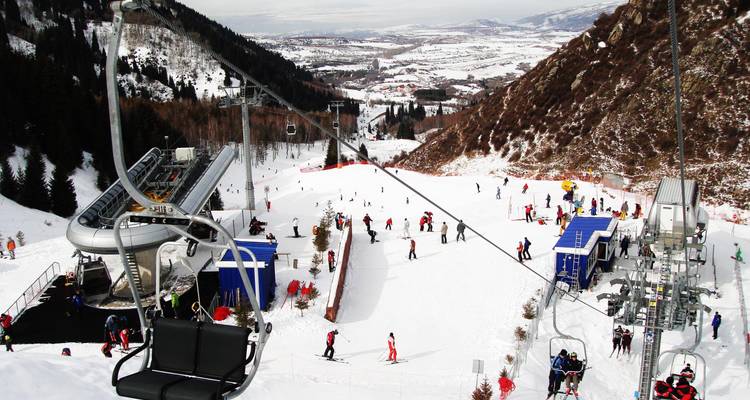 View from a ski lift over a valley with skiers below.