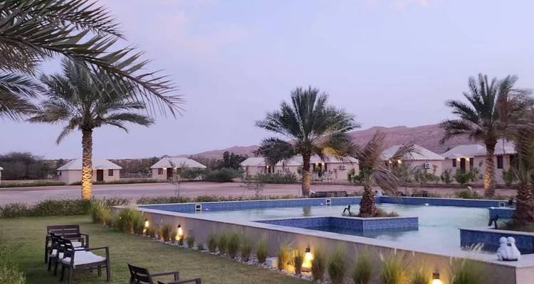 Zone de villégiature avec piscines et palmiers au crépuscule.