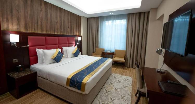 Chambre d'hôtel moderne avec mur d'accent rouge et mobilier soigneusement arrangé.