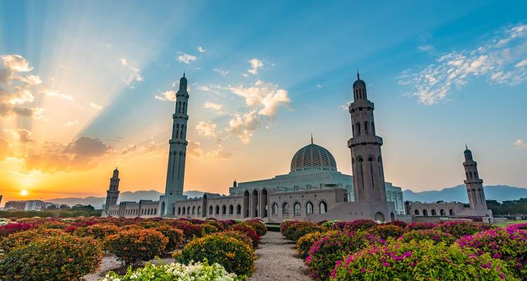 Grande mosquée avec minarets et jardins colorés au lever du soleil.