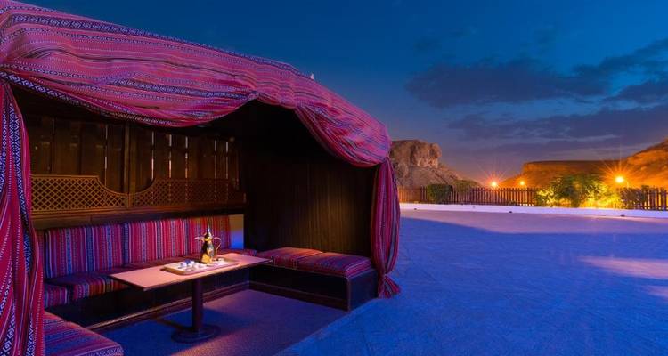 Espace de restauration extérieur avec textiles traditionnels la nuit.