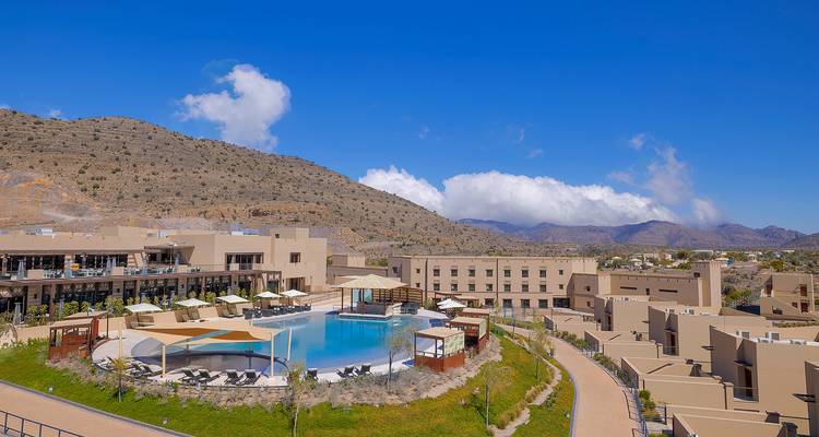 Modernes Resort mit zentralem Pool und bergiger Kulisse.