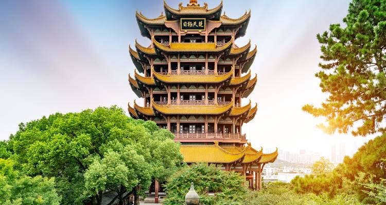 Ein wunderschöner mehrstöckiger Turm mit goldenen Details, umgeben von Grün.