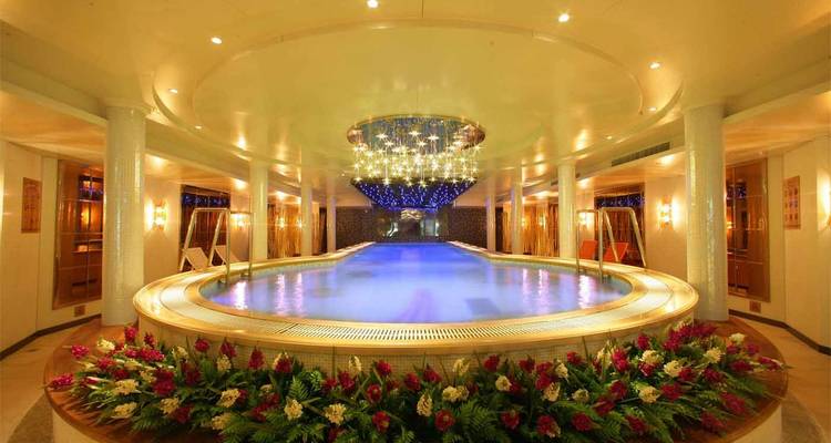 Piscina cubierta de lujo con luces de techo estrellado y decoraciones florales en un crucero.