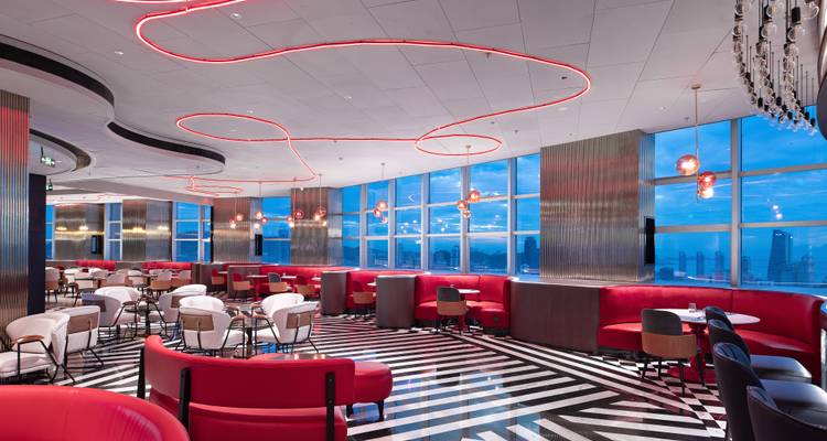 Modernes Restaurant mit rot-thematisierter Einrichtung und Stadtblick.