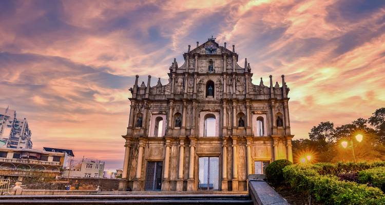 Historische Kirchenfassade bei Sonnenuntergang mit farbenfrohem Himmel dahinter.