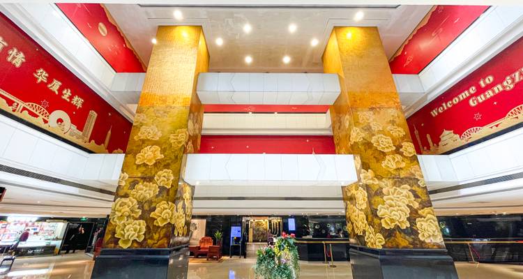 Goldene Säulen und rote Dekoration in einer großen Hotellobby.