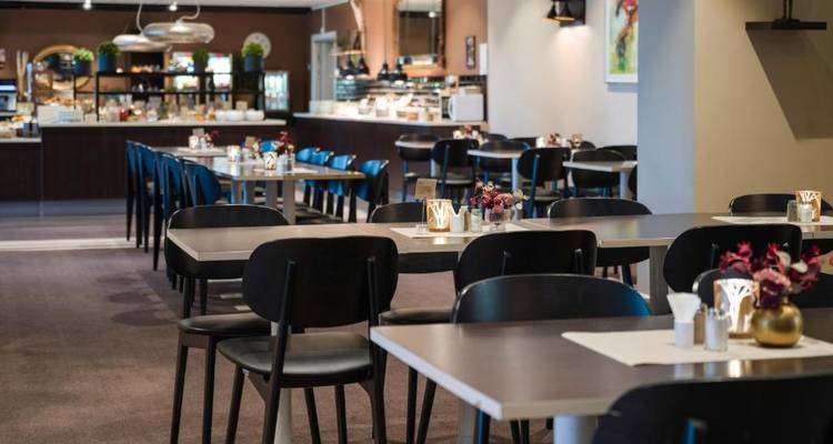 Salle à manger avec tables et chaises soigneusement arrangées.
